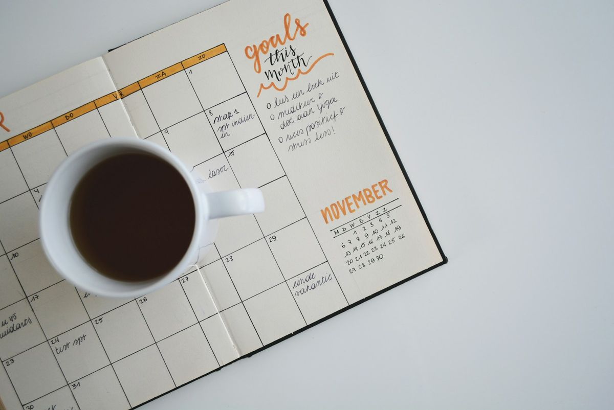 Kalender og notatbok på skrivebord med kaffe